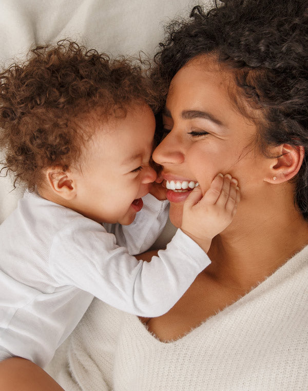 Baby and mother laughing in bed